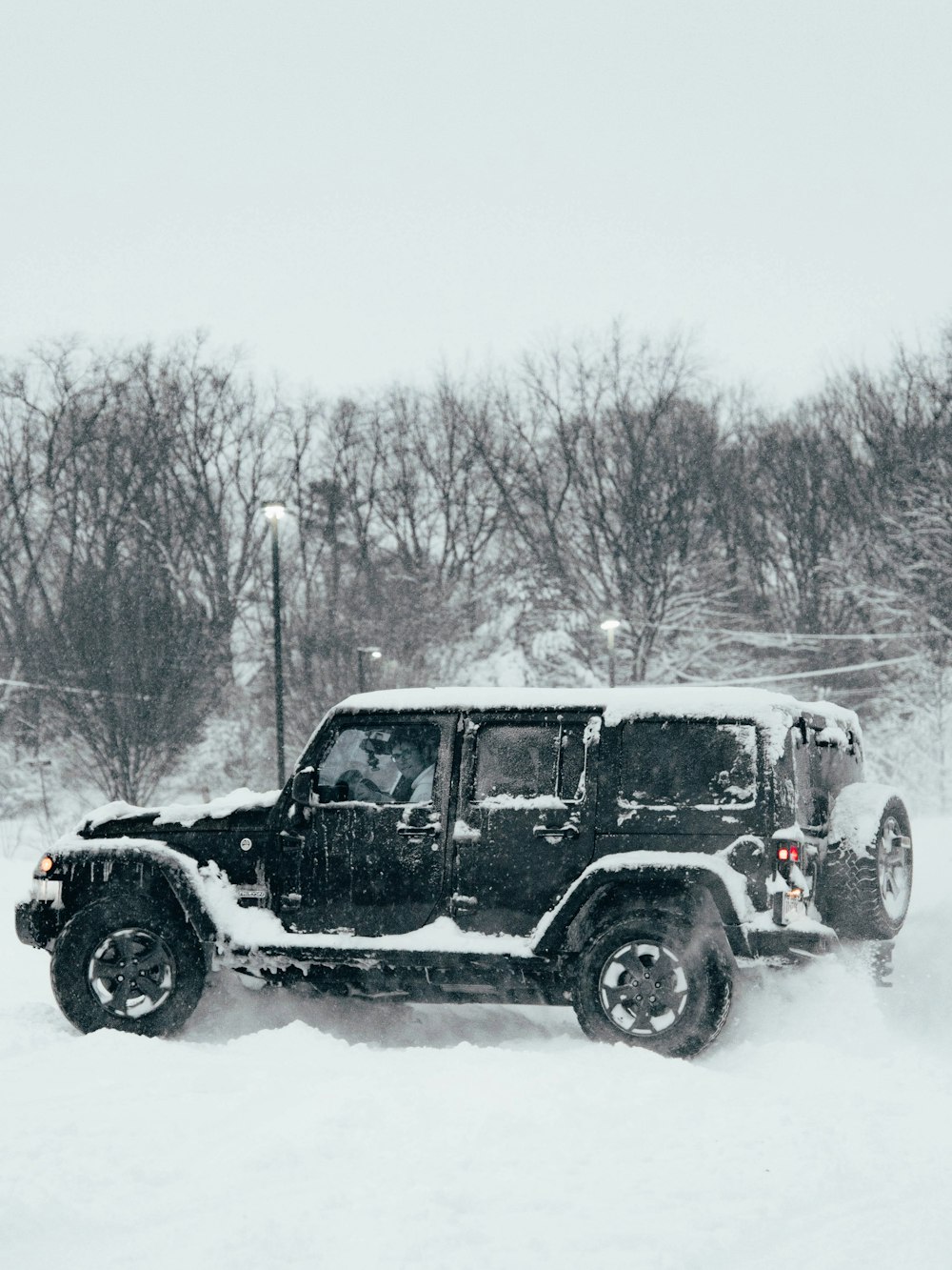 a jeep driving through a snow covered field