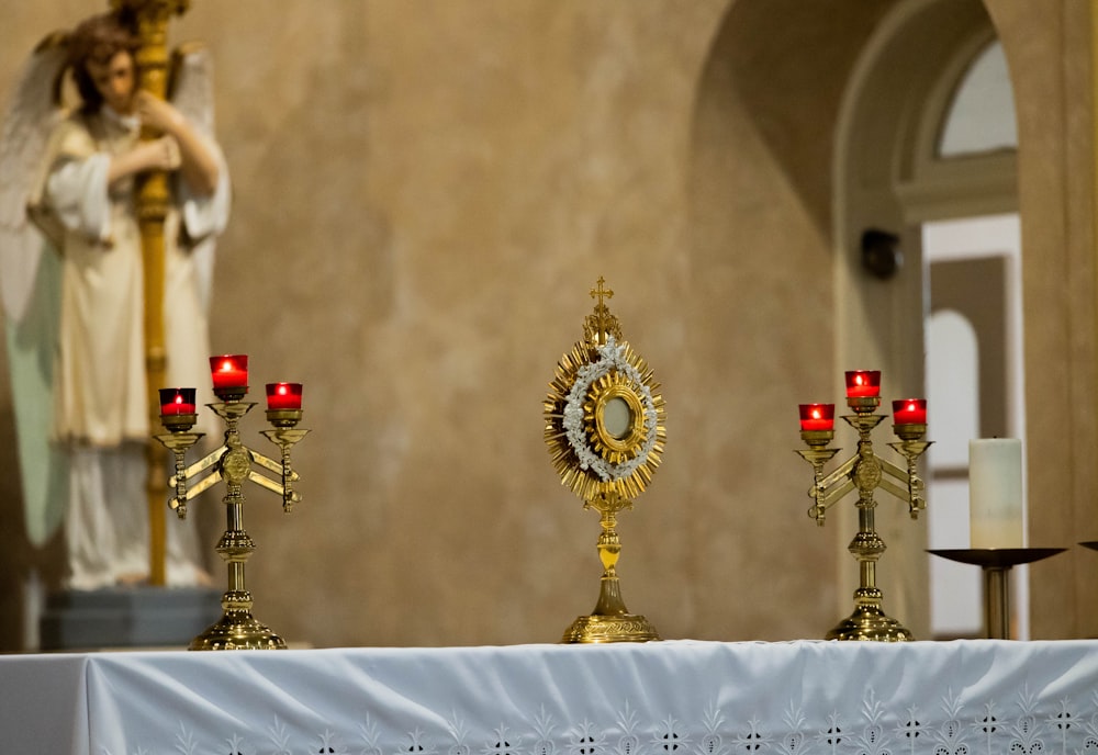 a table topped with candles next to a statue of an angel