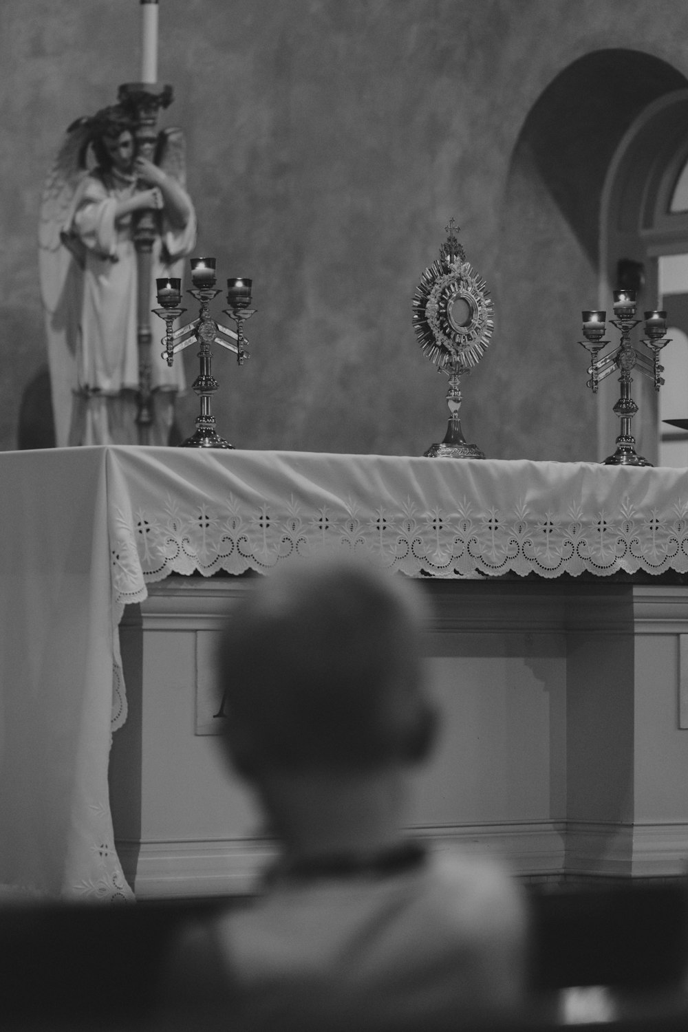 a black and white photo of a priest in a church