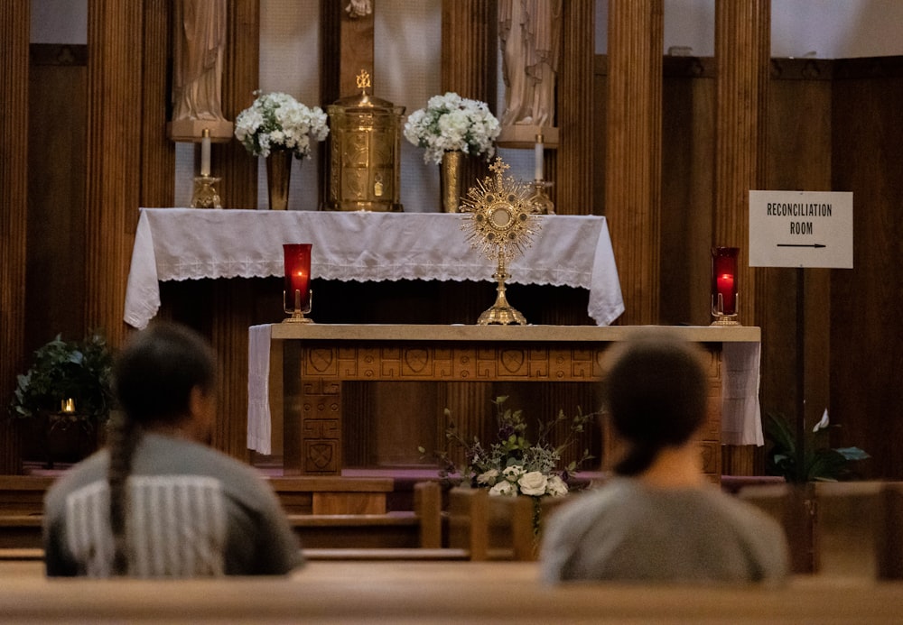 a couple of people sitting in front of a church alter