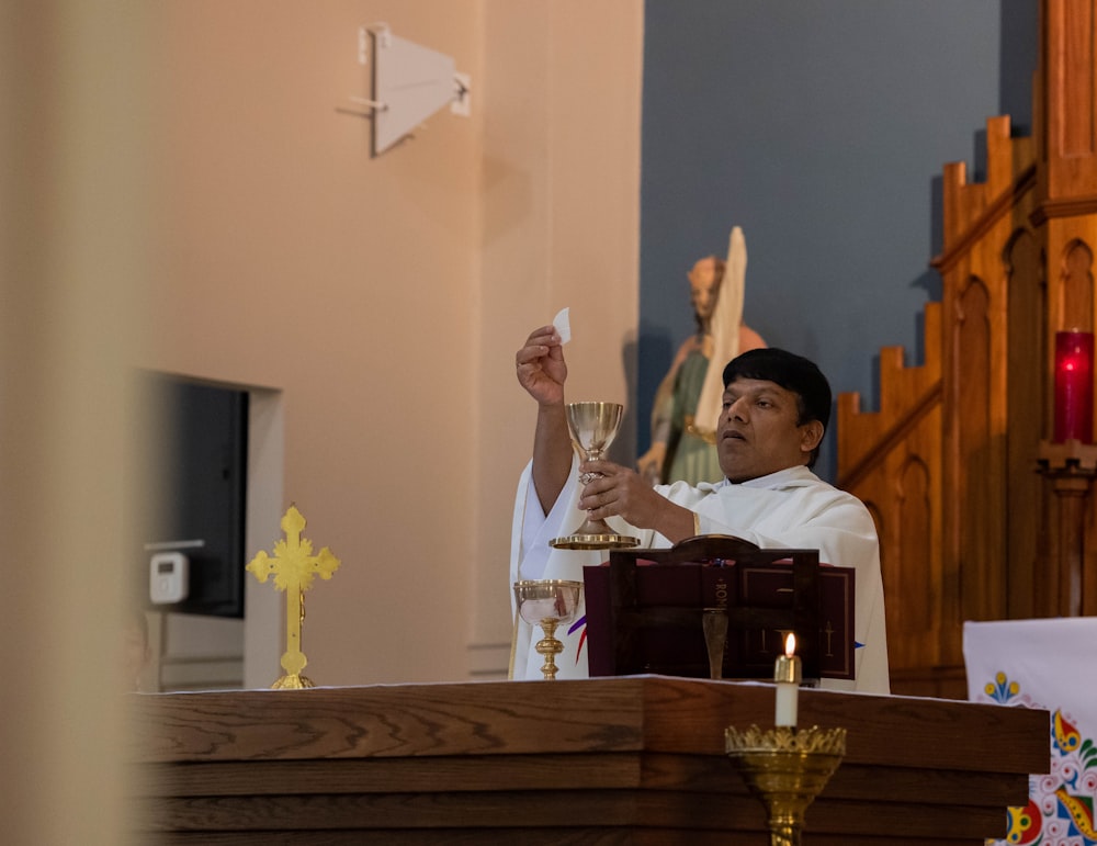 a priest holding a glass of wine in a church