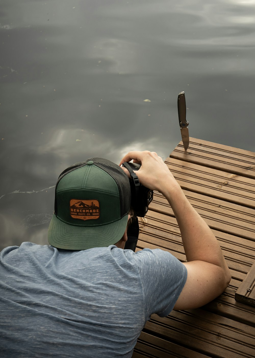a man taking a picture of a bird on a dock