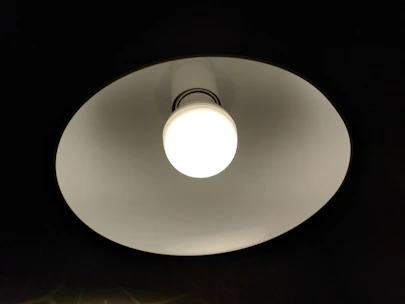An electrician installing a modern lighting fixture in a bright living room.