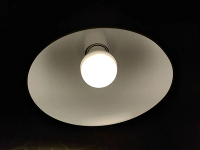 Close-up of hands installing a new light fixture in a bright room.