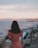 a woman in a pink dress looking out at the ocean