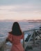 a woman in a pink dress looking out at the ocean