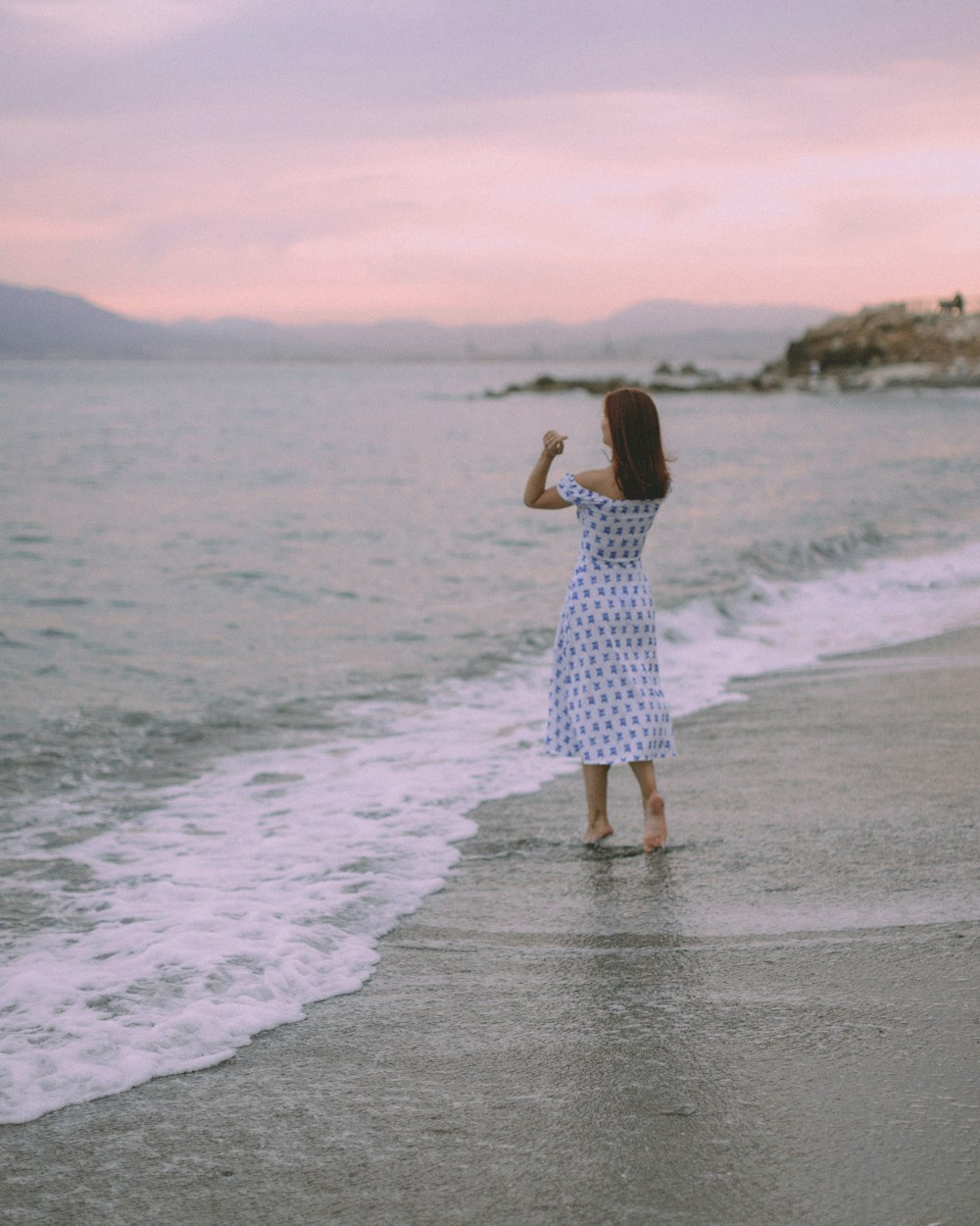 uma mulher em pé em cima de uma praia ao lado do oceano