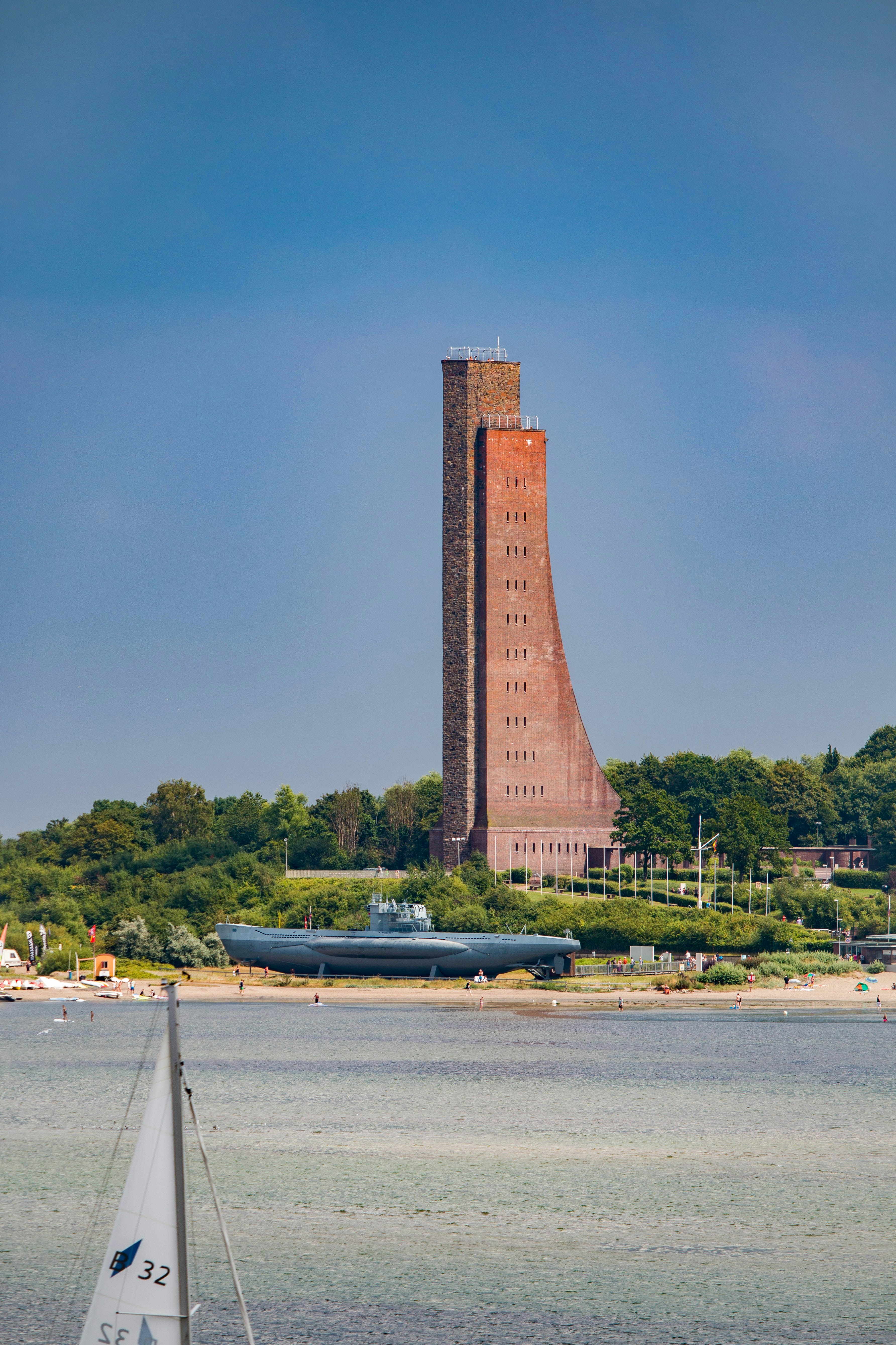a sailboat in the water near a tall tower