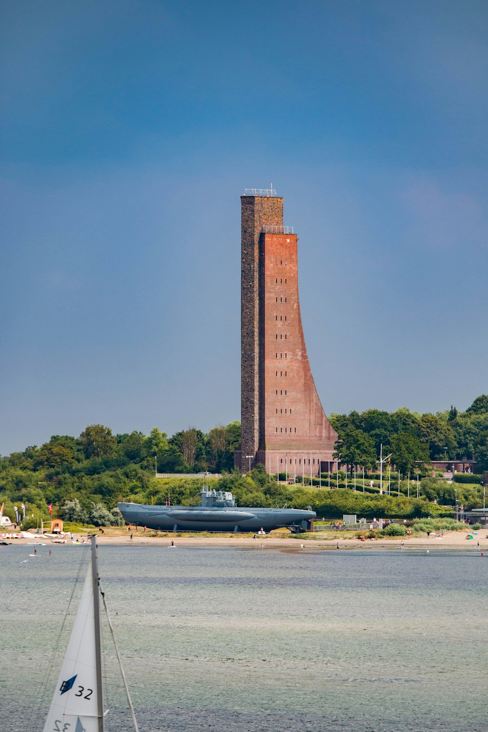 a sailboat in the water near a tall tower