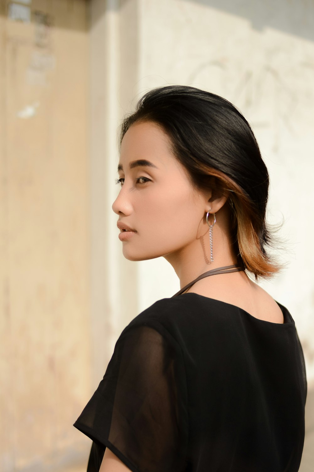 a woman wearing a black top and earrings