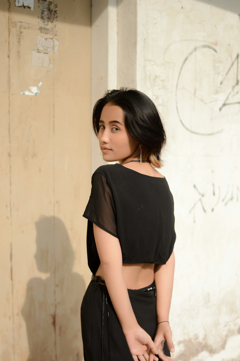 a woman standing in front of a wall with graffiti on it