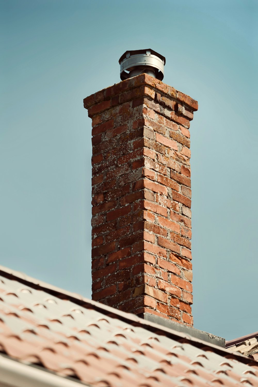 a brick chimney with a weather vane on top of it