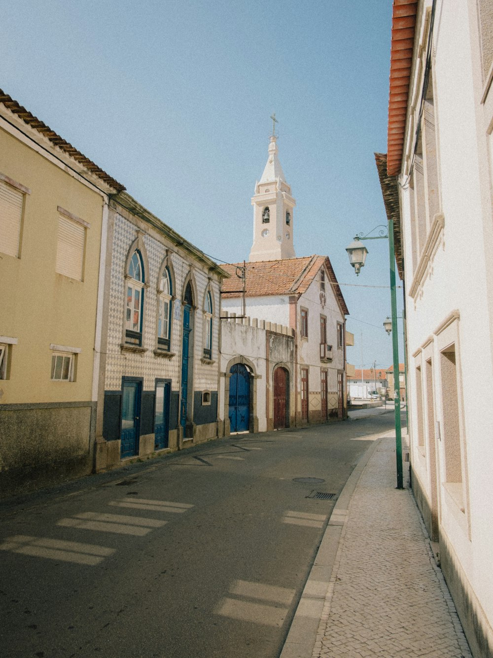 a narrow street with a church steeple in the background