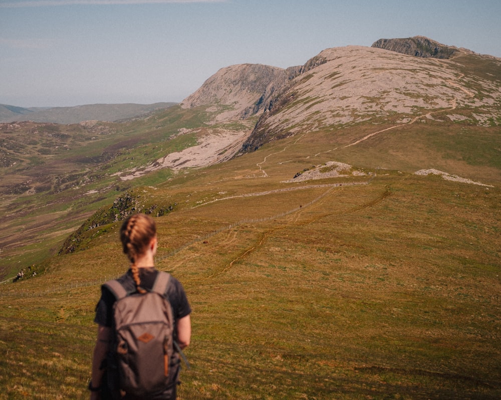 a person with a backpack on a grassy hill