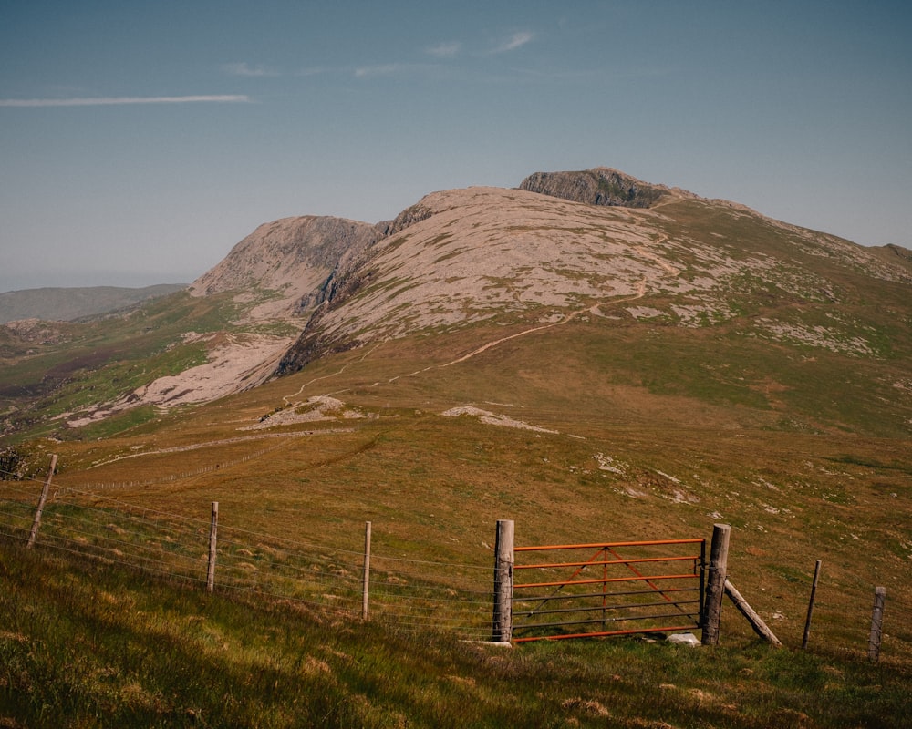 a fence in a field with a mountain in the background