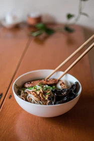 Elegant shot of a steaming bowl of ramen with fresh vegetables and tender meat, glowing warmly.