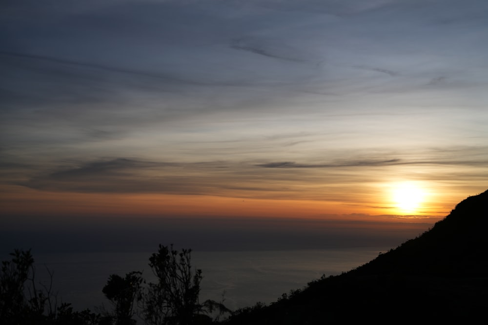 the sun is setting over a mountain top