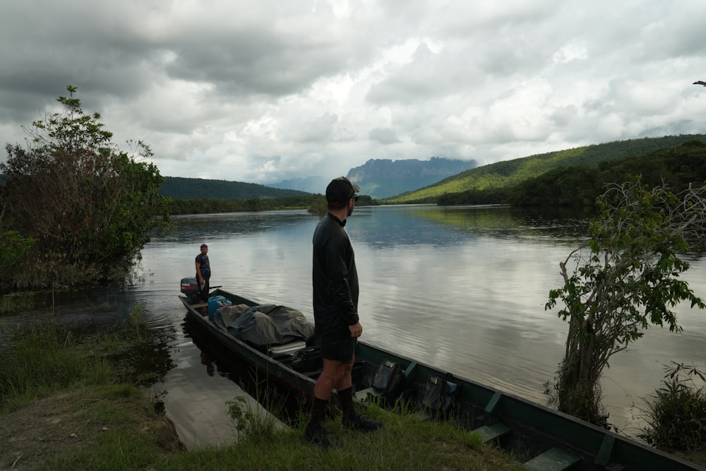 Un homme debout à côté d’un bateau sur un lac