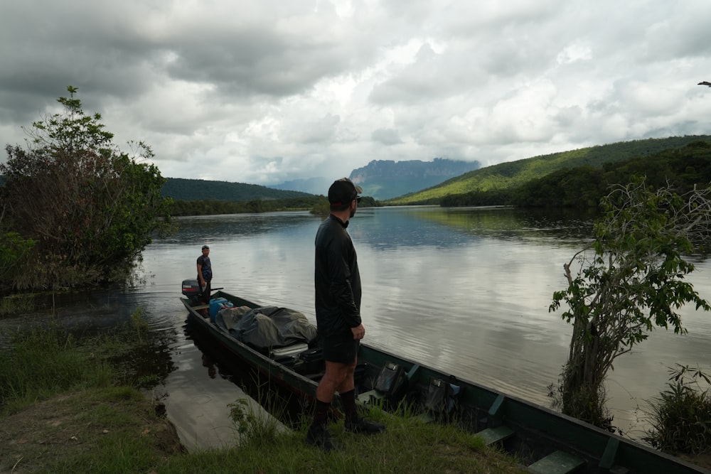 a man standing next to a boat on a lake