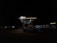 A dimly lit car wash at night features a parked white truck under the illuminated canopy. The sign above reads 'Mister' with a yellow glow, while another sign on a nearby building displays 'Mister Car Wash'. The surrounding area is dark with few visible details.
