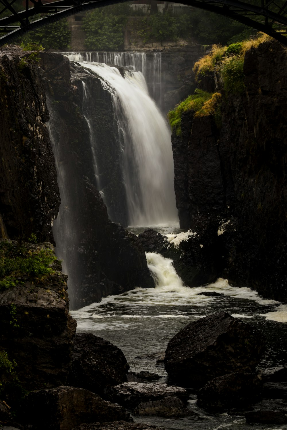 a large waterfall with a bridge over it