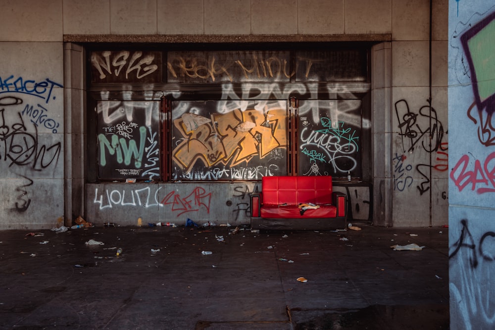 a red chair sitting in front of a graffiti covered building