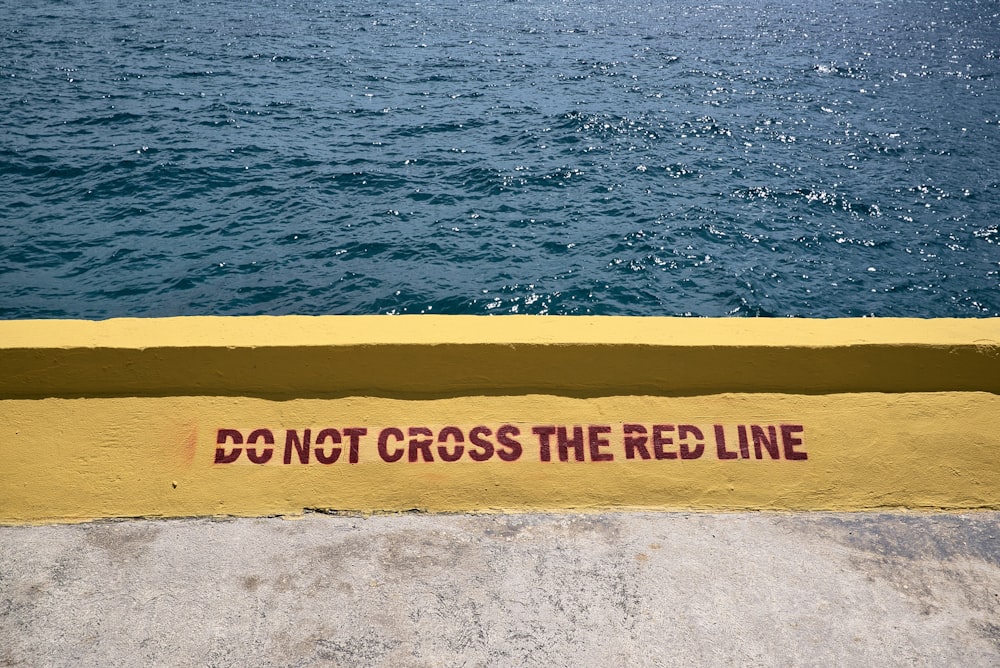 a sign on the side of a yellow wall that says don't cross the