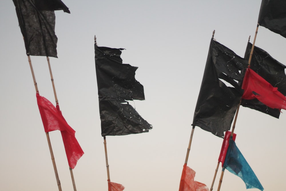 um grupo de bandeiras pretas e vermelhas voando no céu