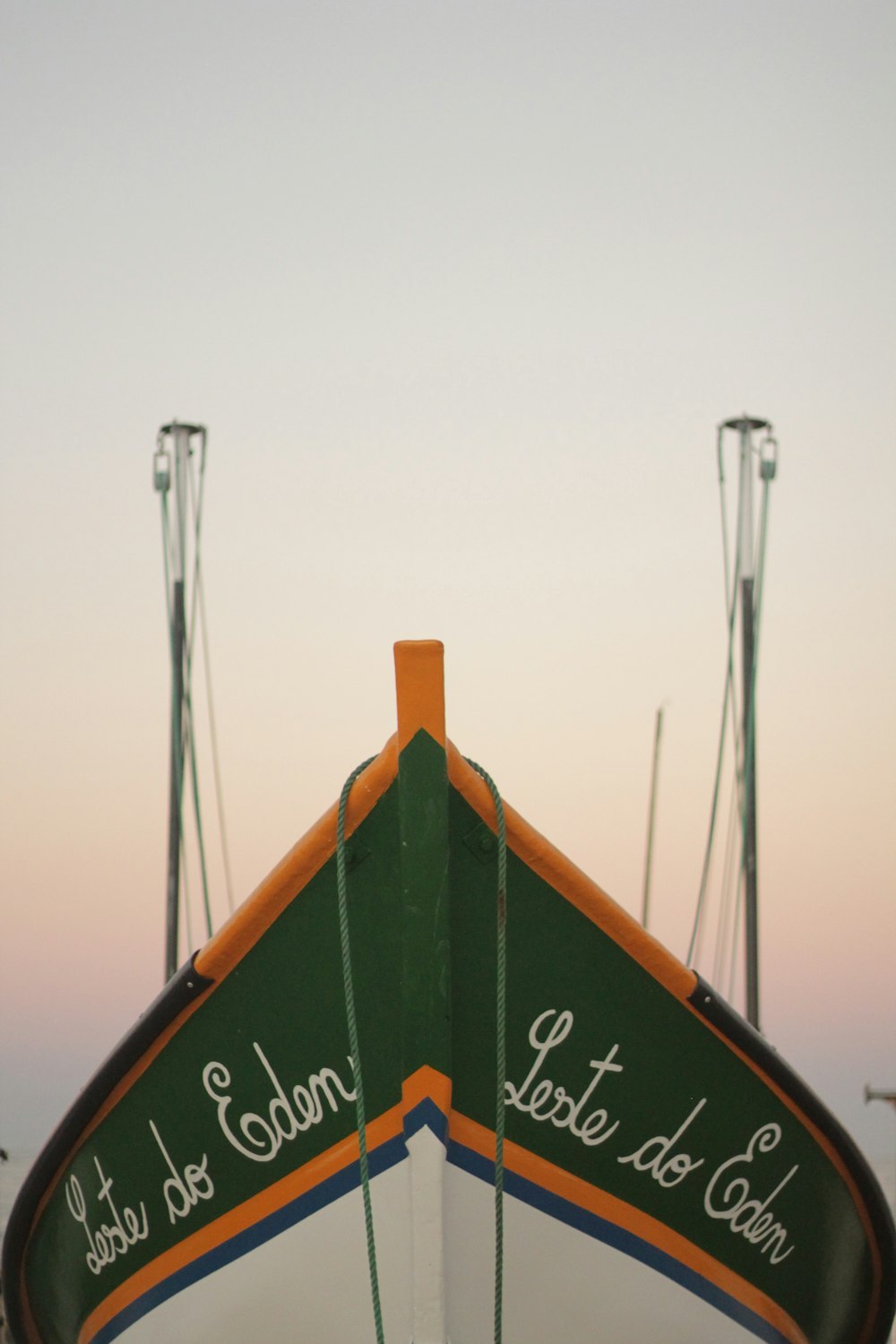 a green and white boat sitting on top of a beach