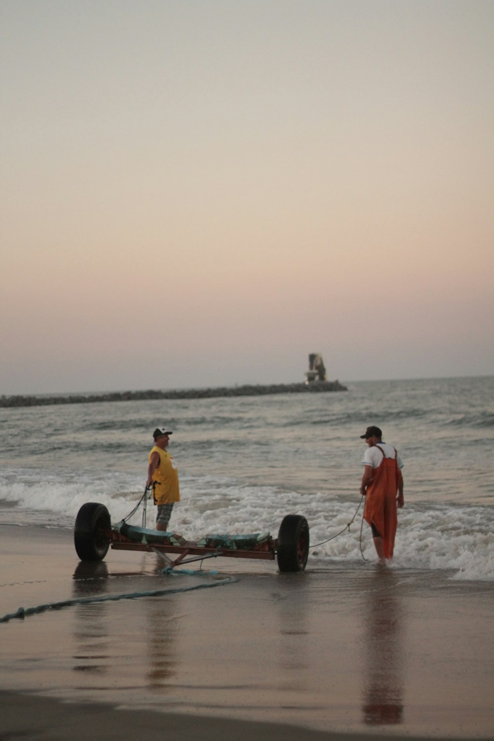 a couple of men standing on top of a beach next to the ocean