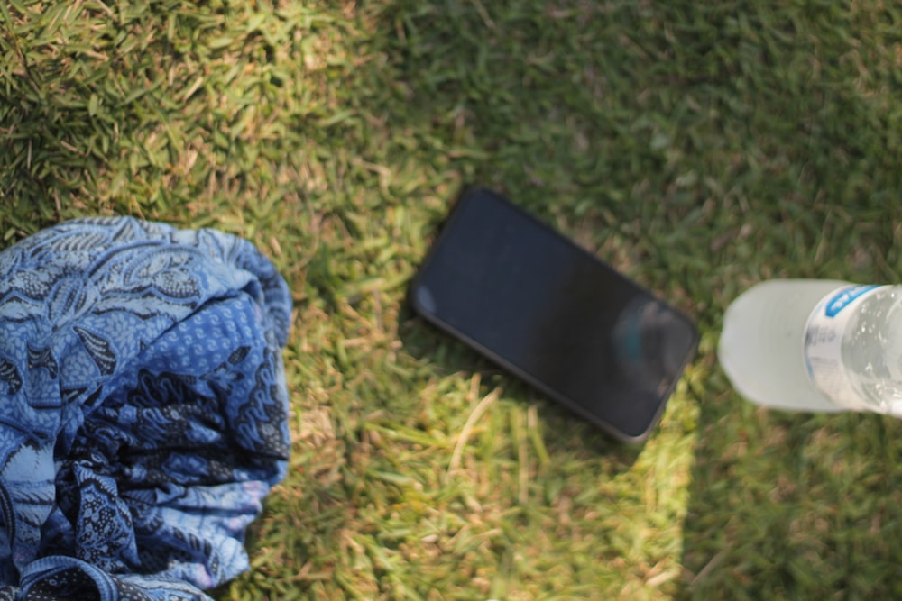 a bottle of water and a cell phone on the grass