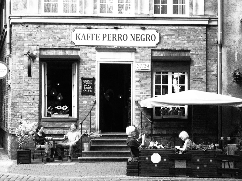 a black and white photo of people sitting outside of a restaurant