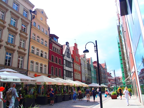 A vibrant city street scene outside a boutique hotel, showcasing diverse architecture and lively atmosphere.