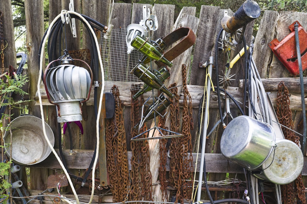 a bunch of metal pots and pans hanging on a fence