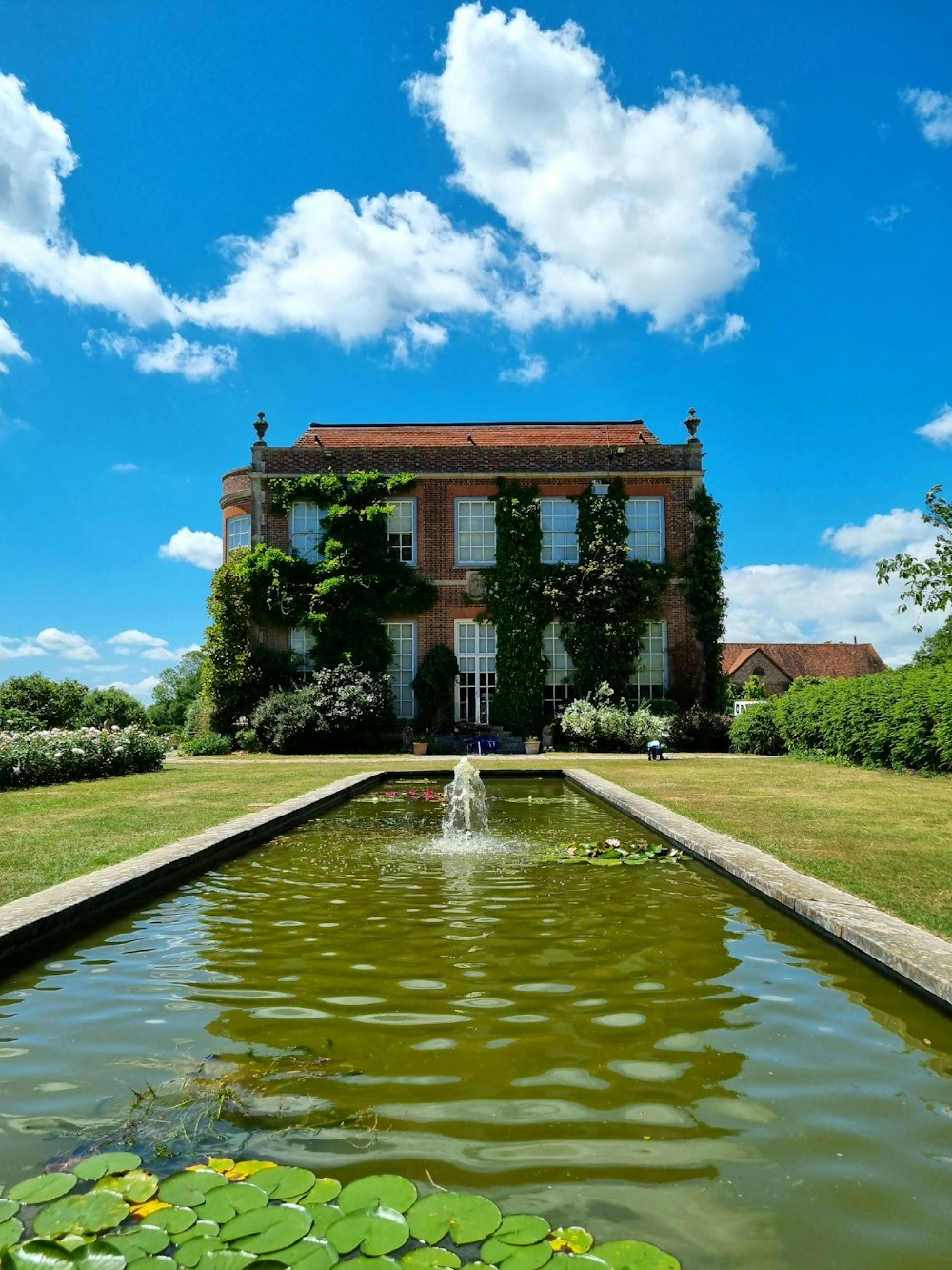 uma casa grande com uma lagoa à sua frente