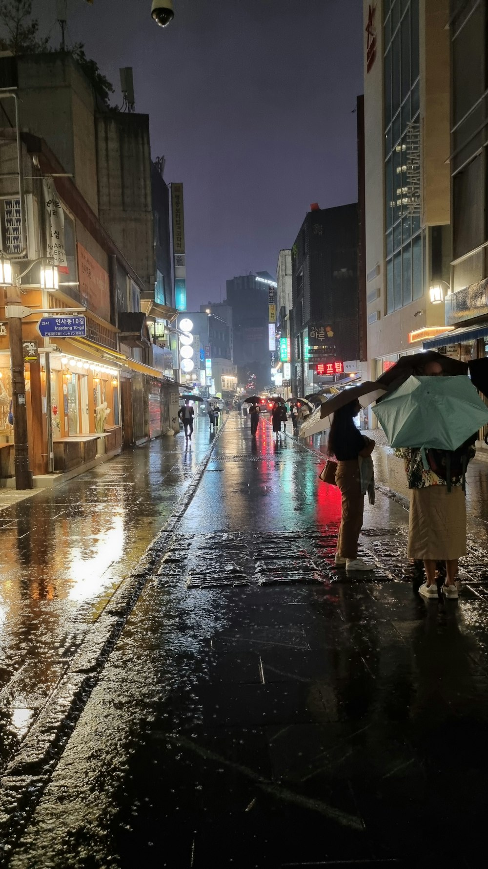 a couple of people walking down a street holding umbrellas