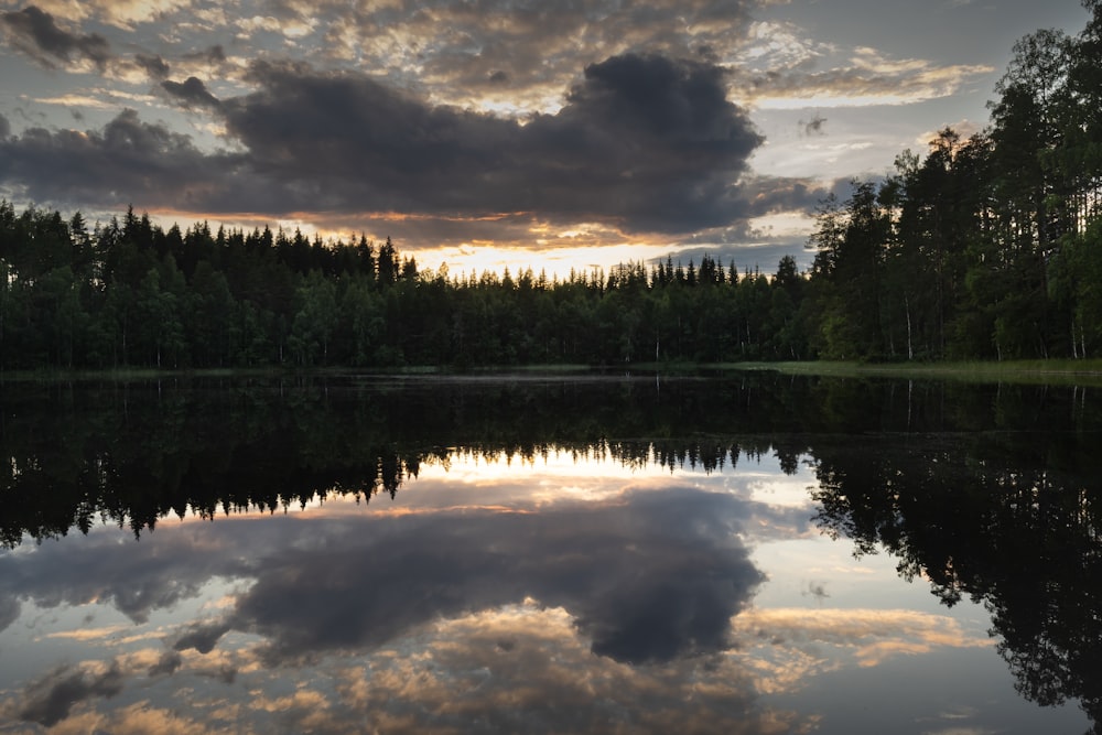 Un lago rodeado de árboles con una puesta de sol al fondo