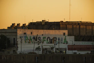 Artist painting a colorful urban mural on a city wall during sunset.