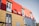 A brightly colored building features red, yellow, and blue corrugated panels. The structure includes several windows with white frames and small balconies. Signs with Spanish text are visible, adding a cultural element to the vibrant facade.