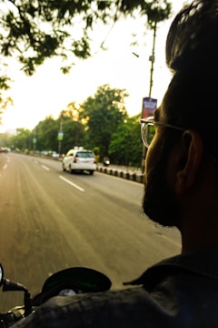 Delivery rider on a motorcycle navigating through city traffic during sunset.
