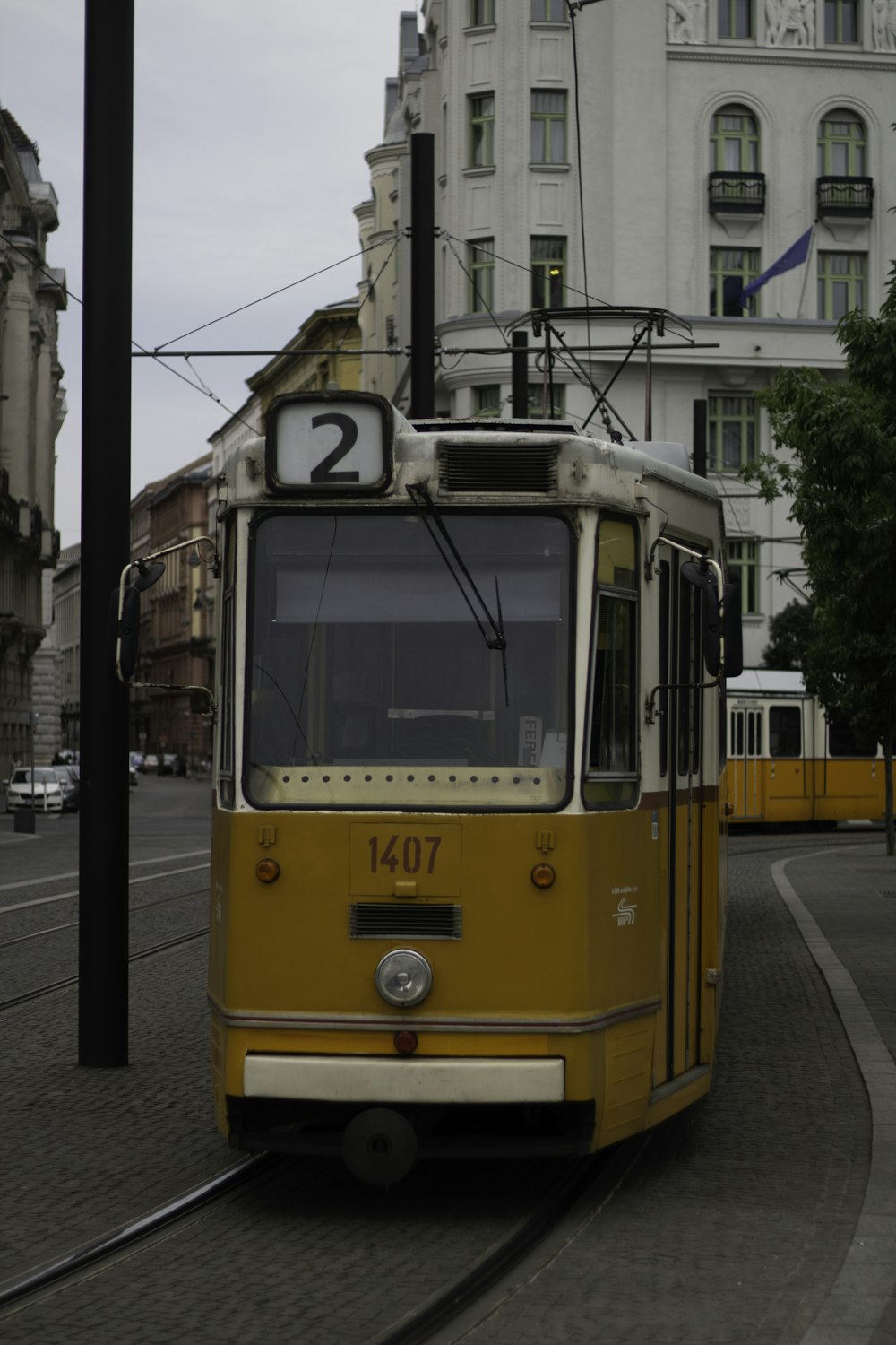 a yellow trolley car traveling down a street next to a tall building