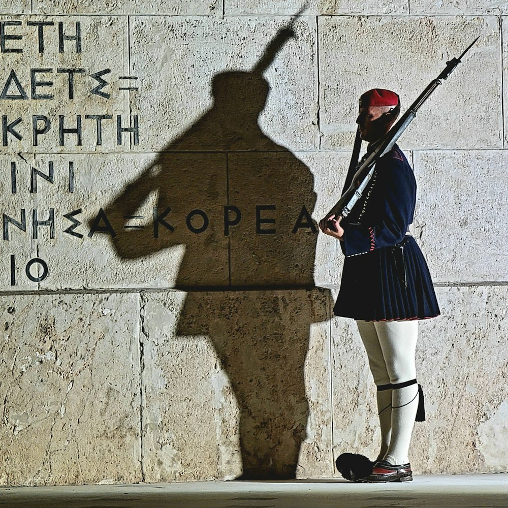 a man in uniform standing next to a wall with writing on it
