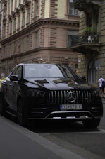 A sleek black luxury car parked in front of a historic London landmark at sunset.