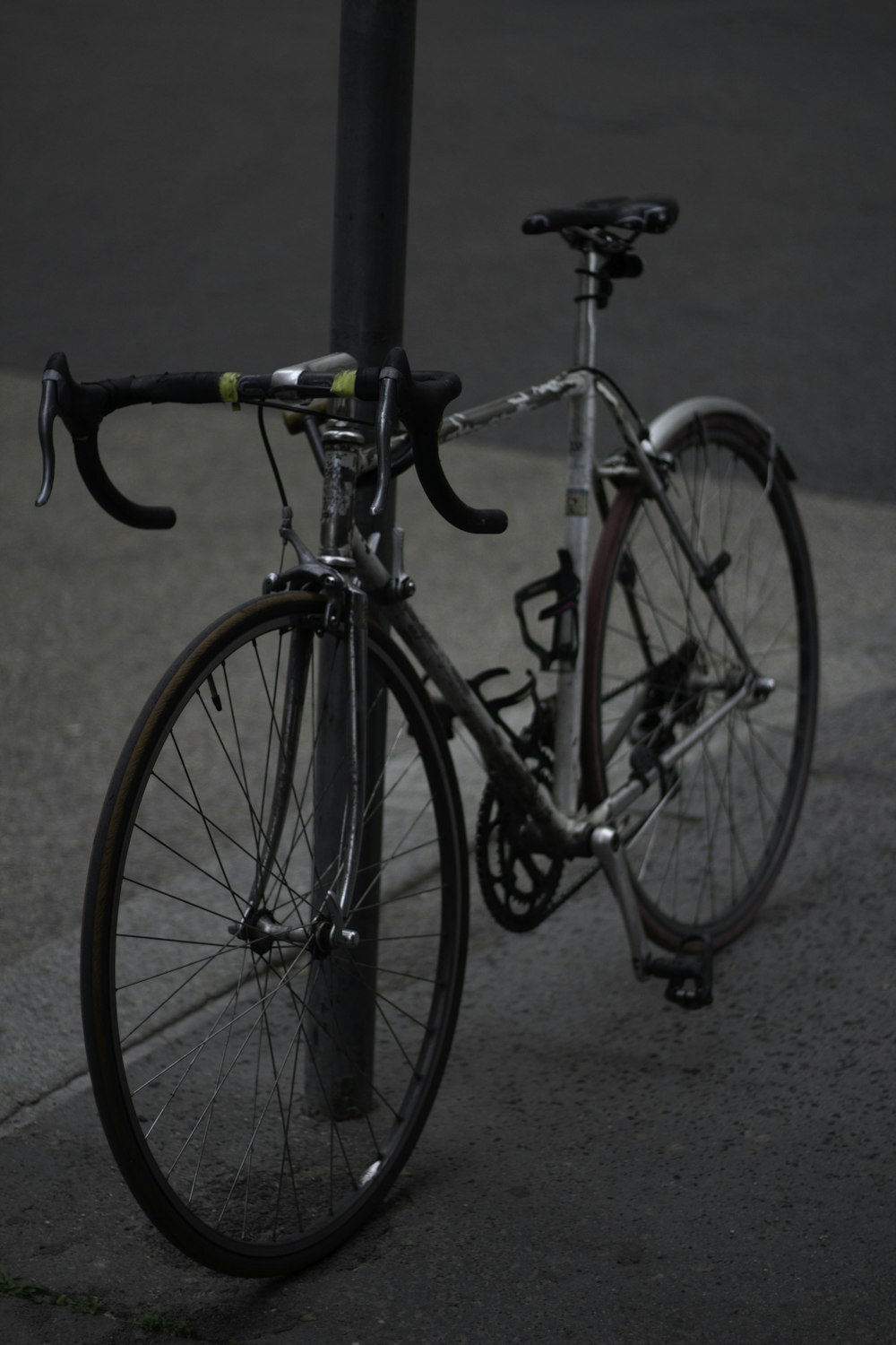 a bicycle parked next to a pole on a street