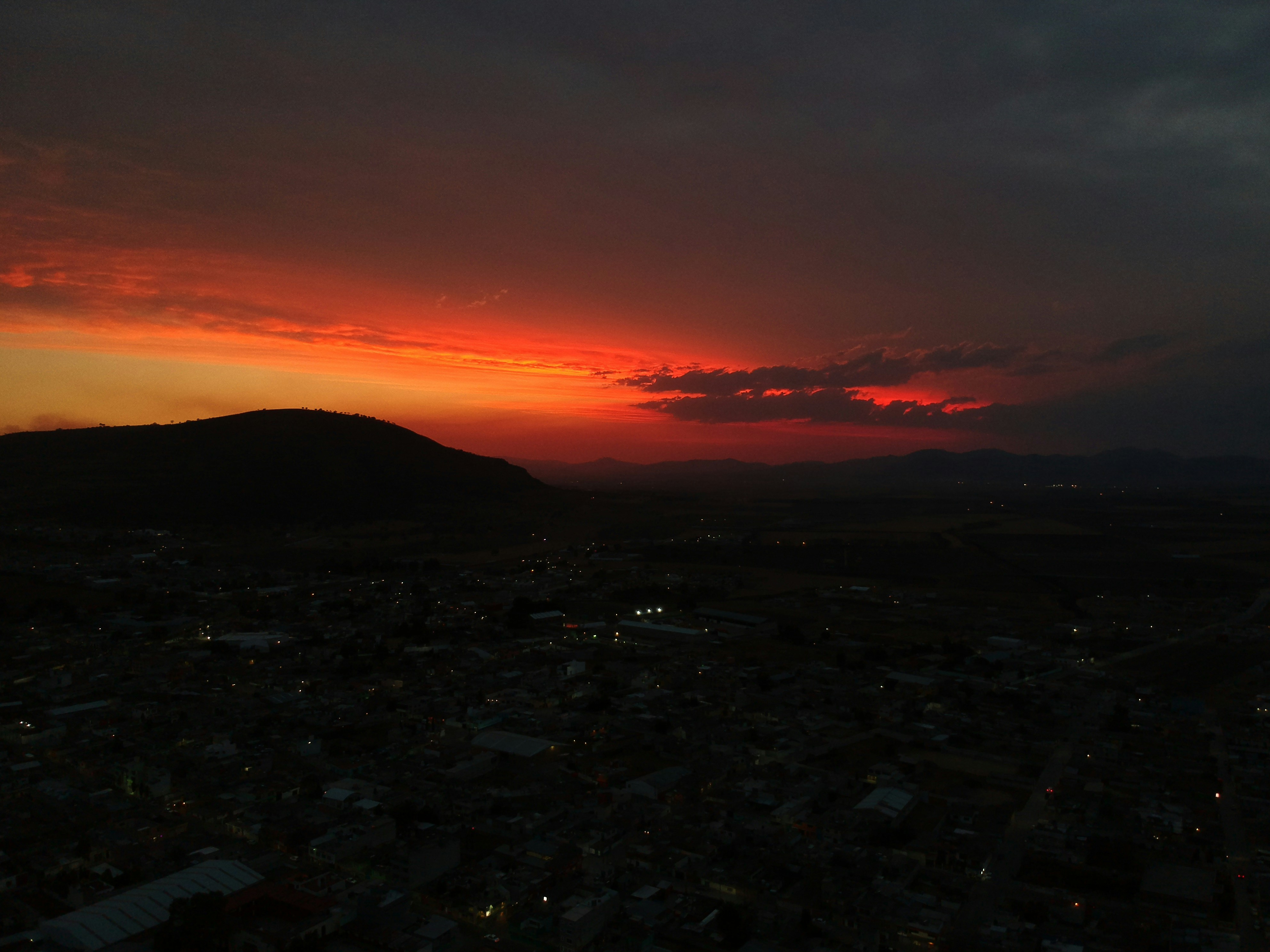 a sunset over a city with a mountain in the background
