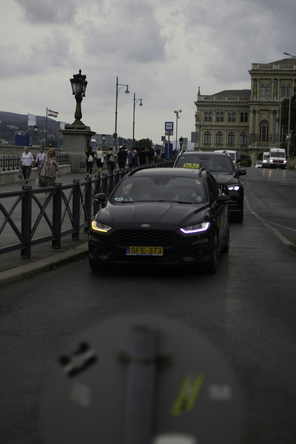 a black car driving down a street next to a bridge
