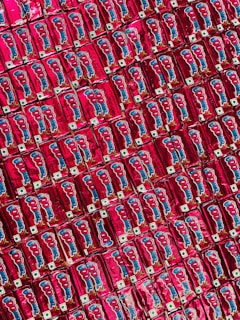 A repeated pattern of red packaged snacks with cartoon graphics and logos, neatly arranged side by side creating a colorful and symmetrical display.