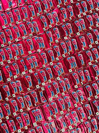 A repeated pattern of red packaged snacks with cartoon graphics and logos, neatly arranged side by side creating a colorful and symmetrical display.