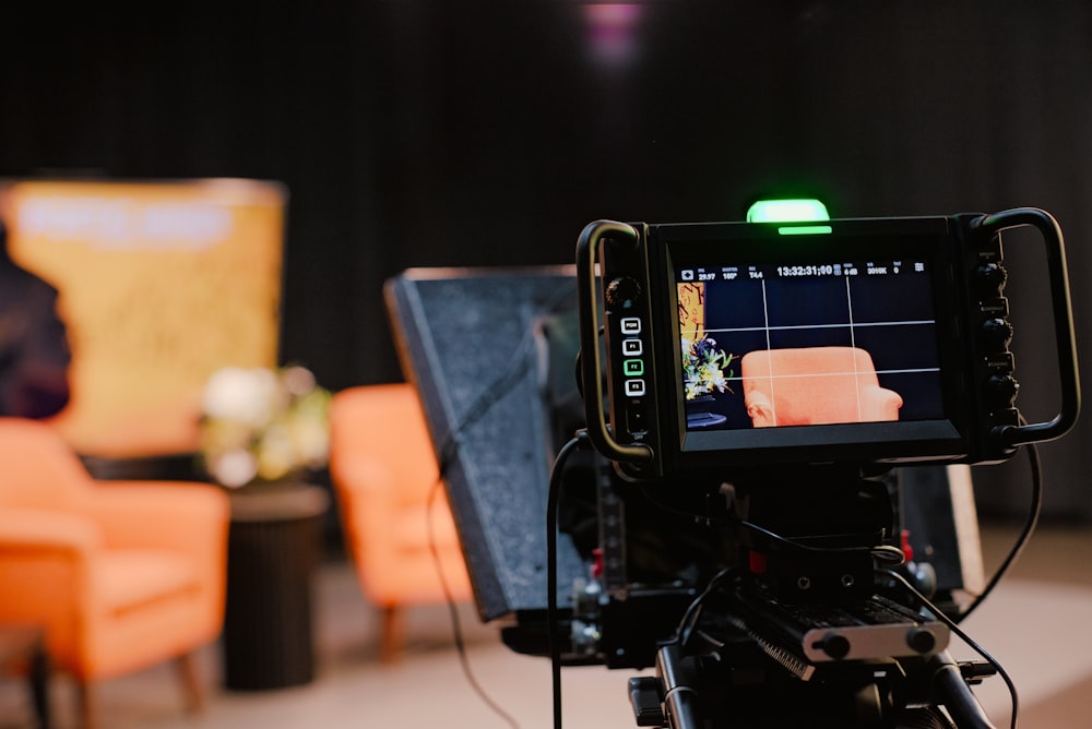 a camera set up on a tripod with a chair in the background