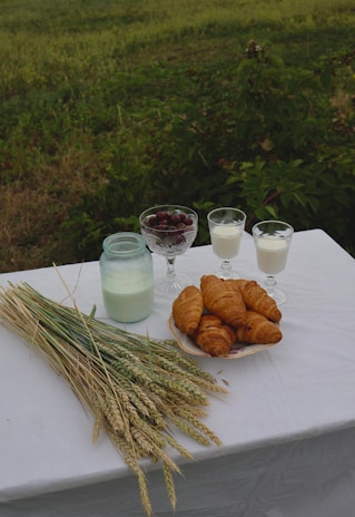 Fresh dairy products arranged on a rustic wooden table with green leaves in the background.